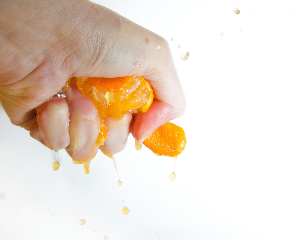 a hand squeezing an orange